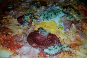 Detail Pizza Rusticale mit Spiegelei, Salami, Schinken, Speck, Mais und viiiiel Knoblauch