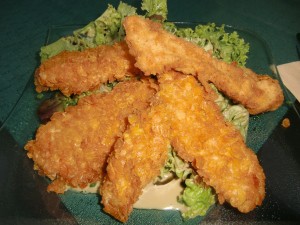 Mit Cornflakes gebackene Hühnerbruststreifen auf Blattsalat mit Kernölmarinade